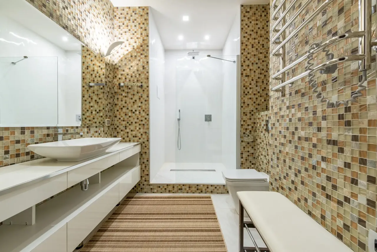 Bathroom with a long vanity, mosaic accent tile, and a glass shower enclosure
