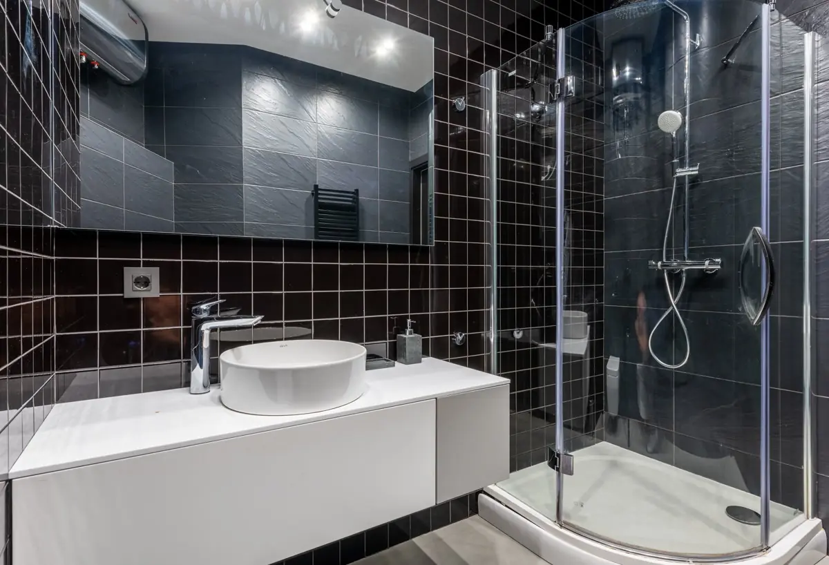 Fully tiled shower enclosure with tight, evenly spaced grout joints across the wet wall and a glass door