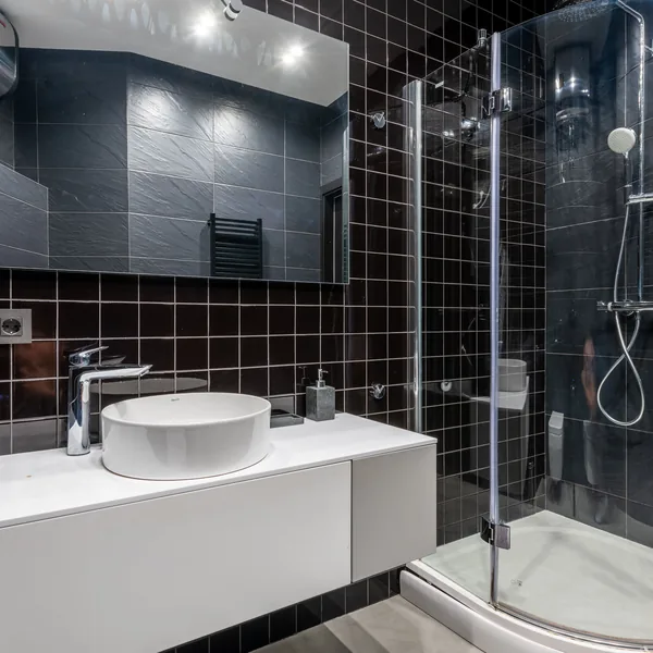 Fully tiled shower enclosure with tight, evenly spaced grout joints across the wet wall and a glass door