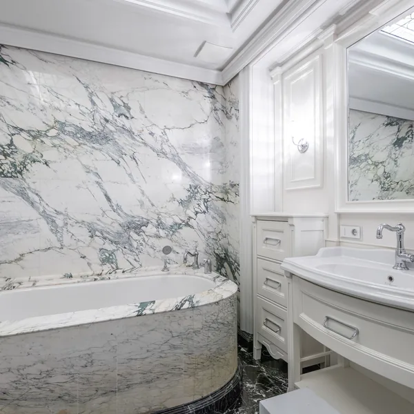 Marble-clad bathroom with a built-in soaking tub and a matching vanity surround
