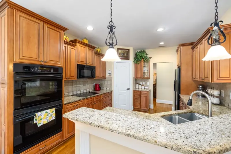 Oak kitchen cabinets with granite counters and a raised breakfast bar