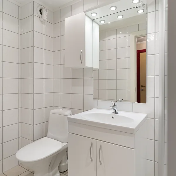 Compact bathroom with a small vanity, white wall tile, and a corner shower
